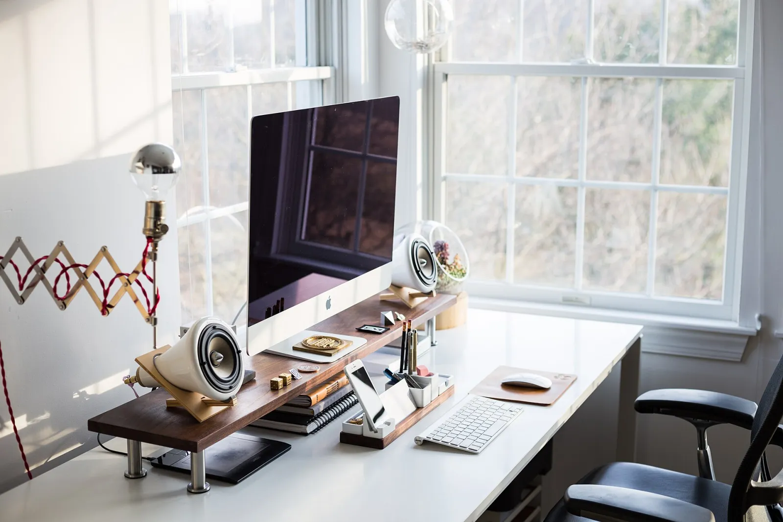 Poste de travail organisé : écran, clavier et accessoires de bureau près d’une fenêtre
