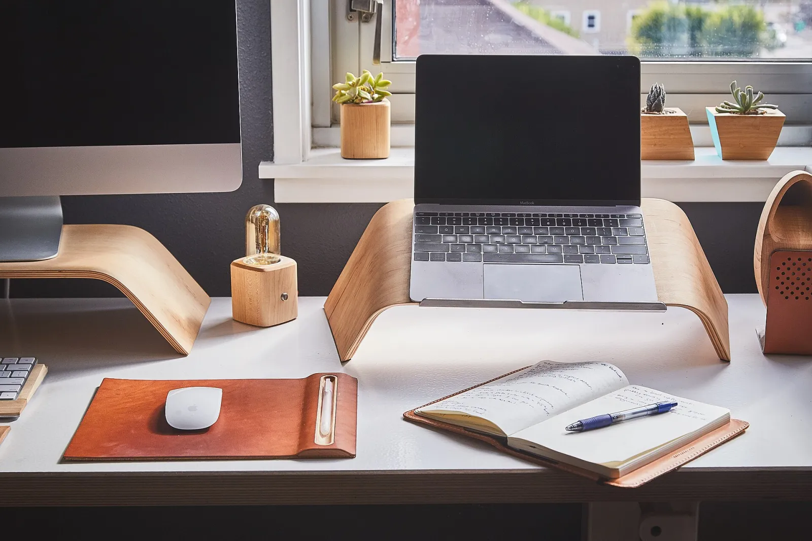 Carnet de notes ouvert et stylo sur un bureau, devant un ordinateur portable